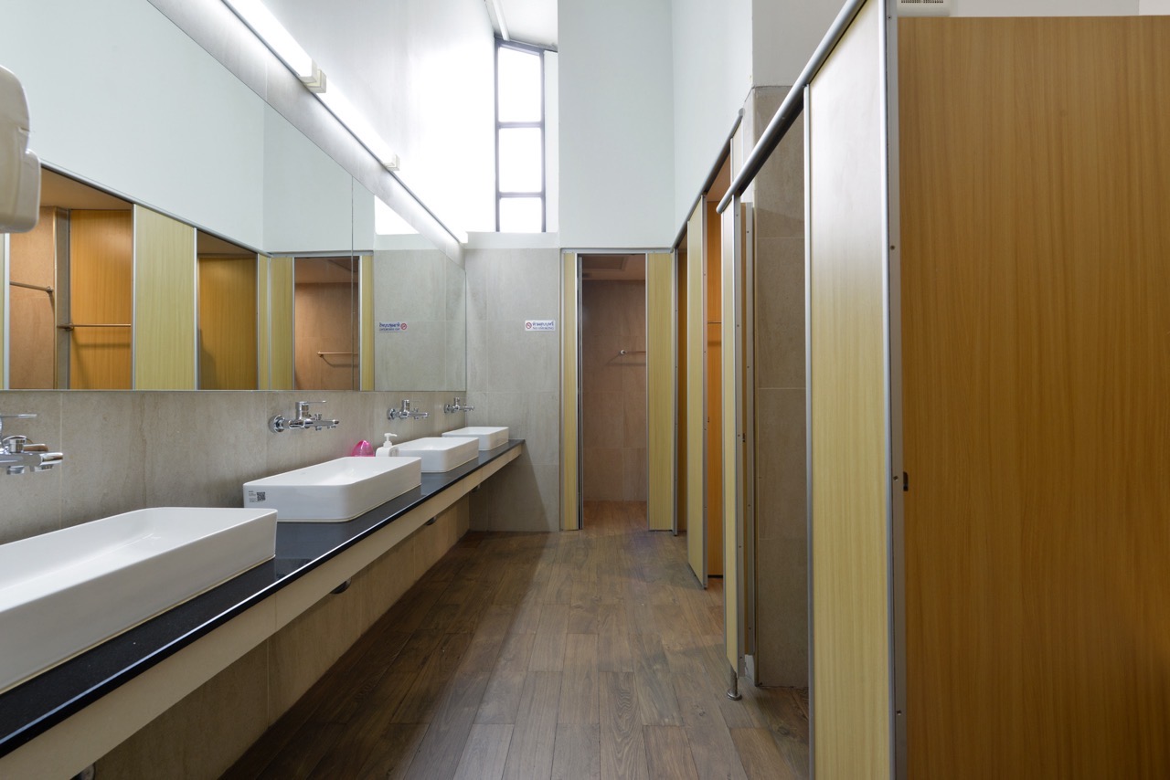 The shared bathroom facilities at StayAt Bedever, with a row of vanities and private shower and toilet stalls
