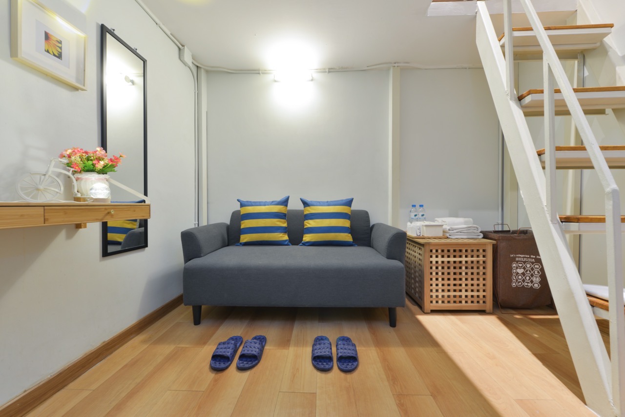 The living area of a Loft Studio at StayAt Bedever, with a sofa and the loft staircase