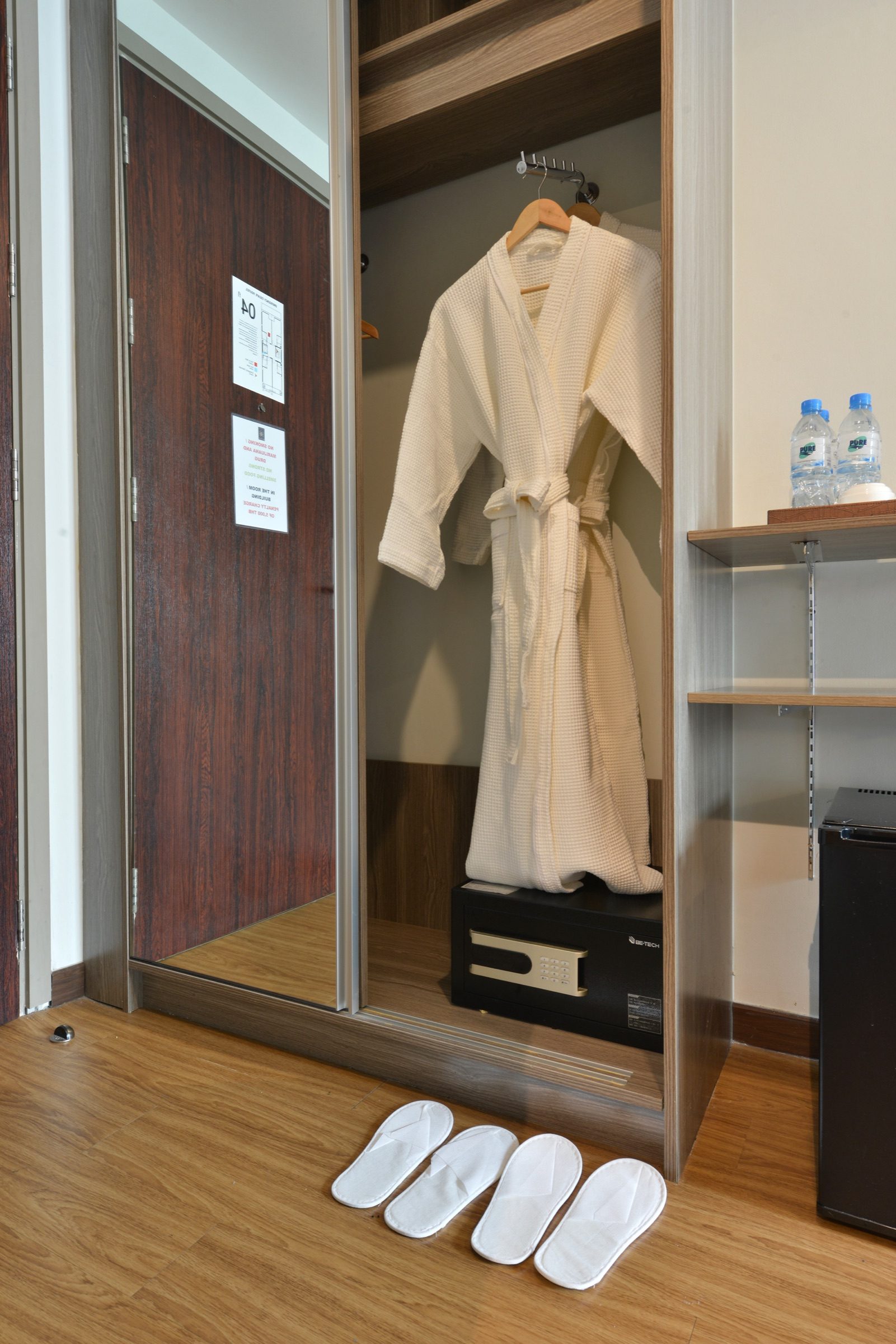 A wardrobe with a robe, safe and slippers in a room at StayAt Bedever