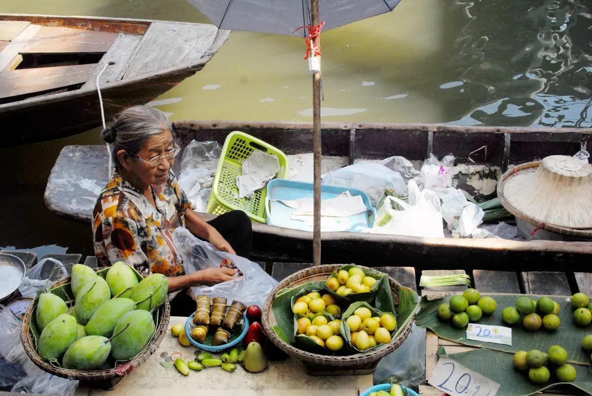 Elderly woman selling fresh fruits at a floating market in Bangkok, Thailand.