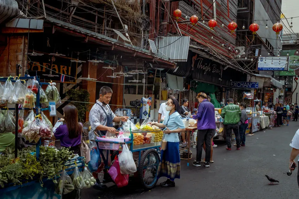 Vibrant street market scene in Asia with diverse vendors selling fresh produce.