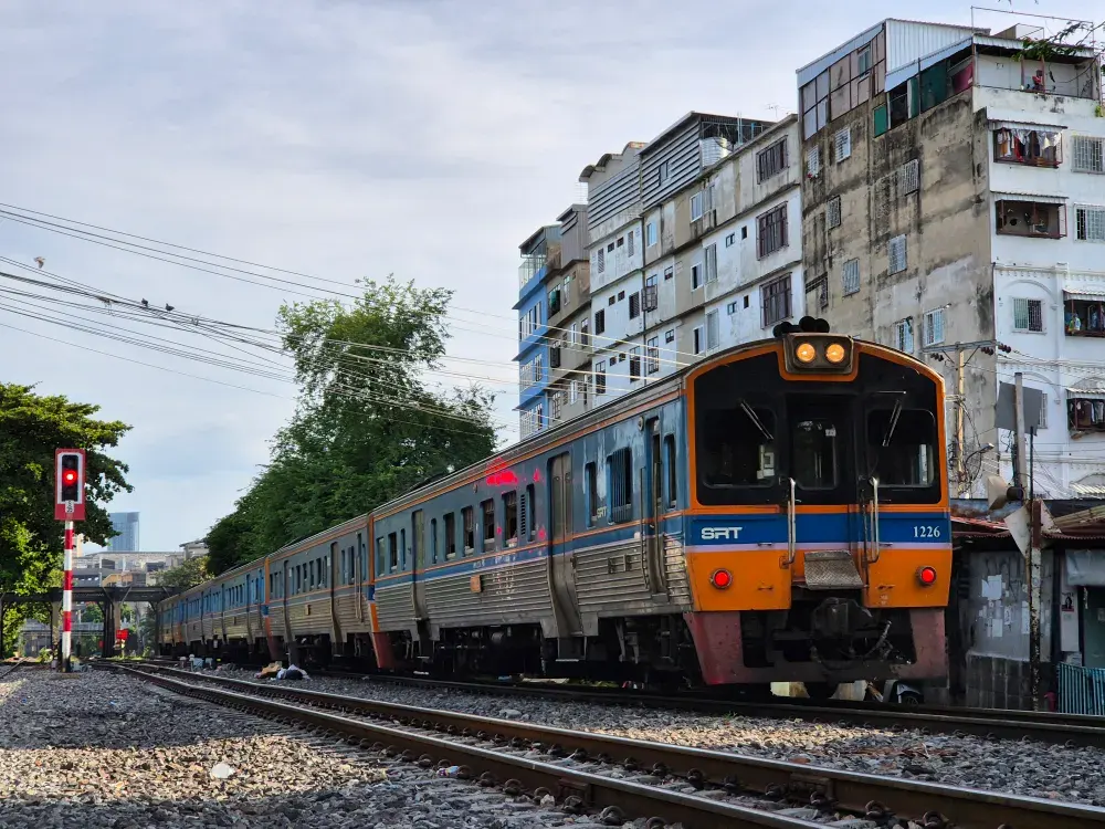 Train in Bangkok passing residential buildings, creating a dynamic urban scene.