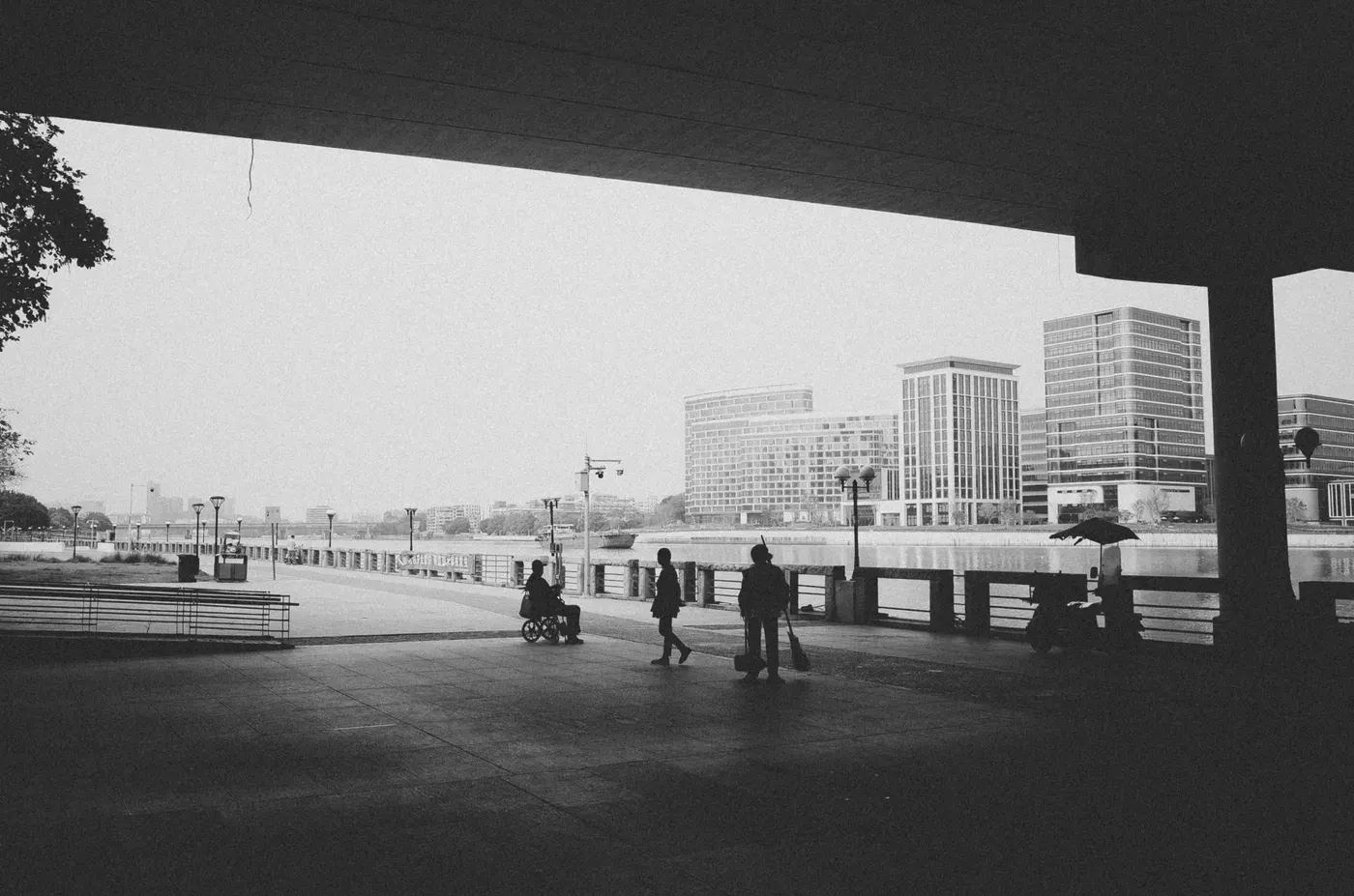 Urban scene with silhouetted figures and city buildings in monochrome.