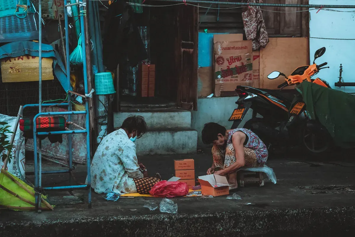 Two people engaged in daily activities on a street in vibrant Bangkok, Thailand.