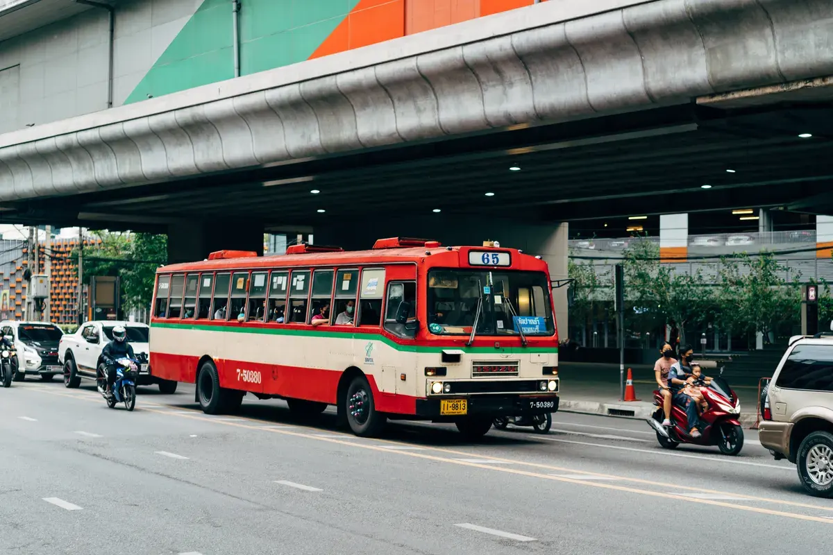 Vibrant red bus amidst dynamic city traffic in Bangkok, Thailand.