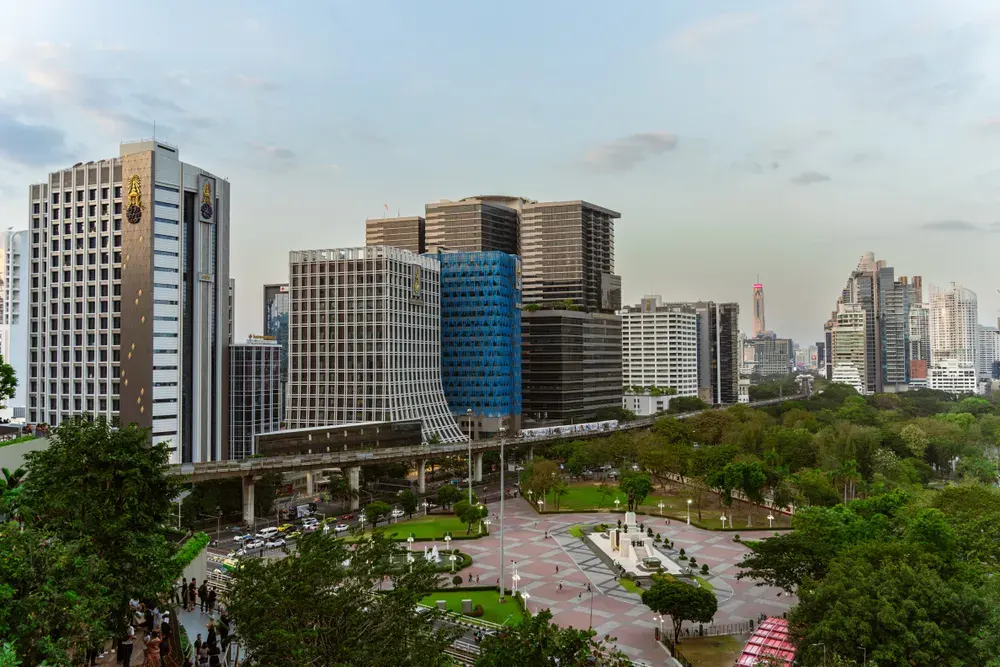 Aerial view of modern skyscrapers and greenery in Bangkok city during daytime, showcasing urban architecture.