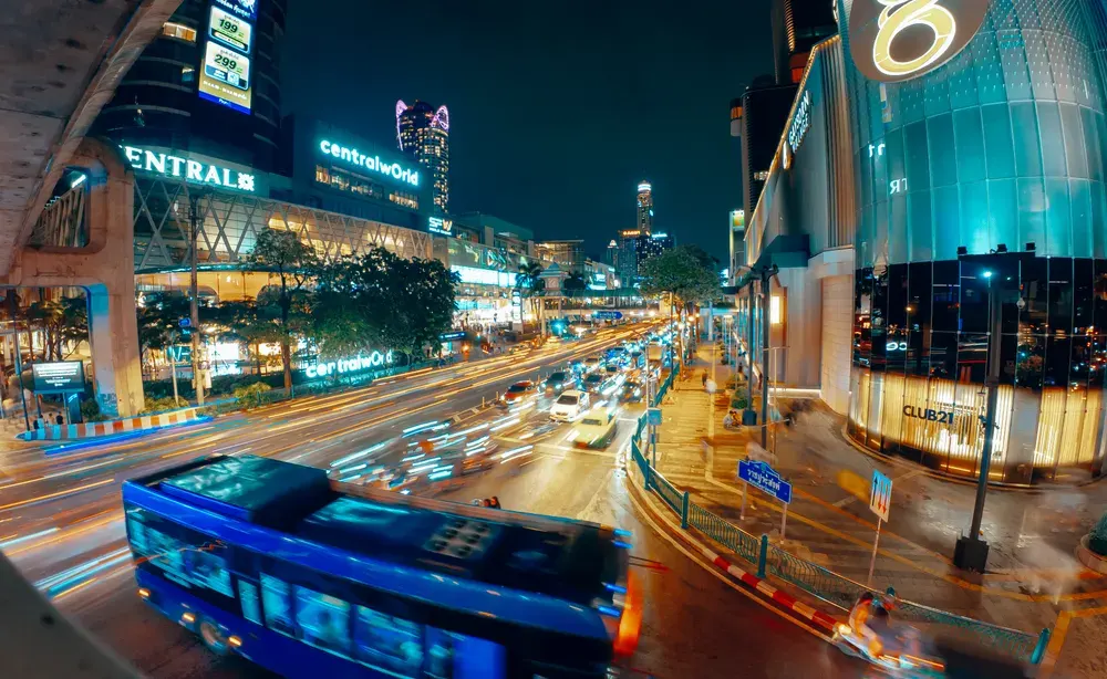Nighttime cityscape featuring bustling traffic and vibrant lights at CentralWorld in Bangkok, Thailand.