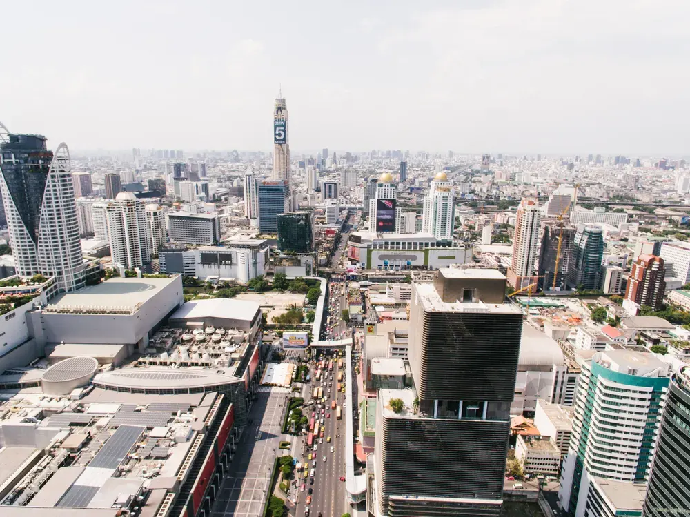 Stunning aerial view of Bangkok's bustling cityscape and skyscrapers on a sunny day.