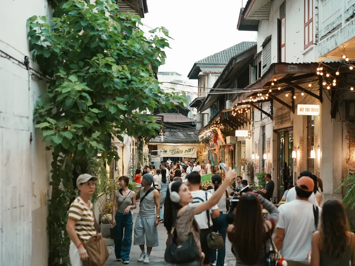A bustling street market scene filled with tourists exploring shops and vibrant street life.