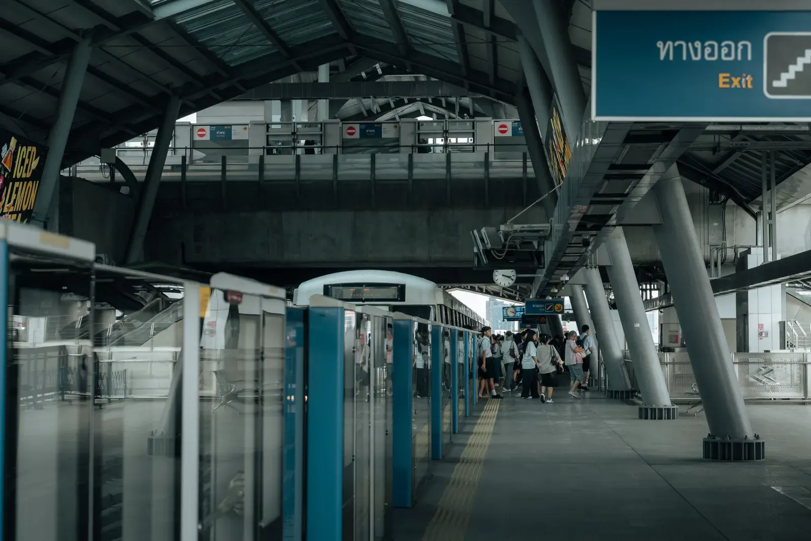 Modern skytrain station in Bangkok with passengers waiting in a covered platform.