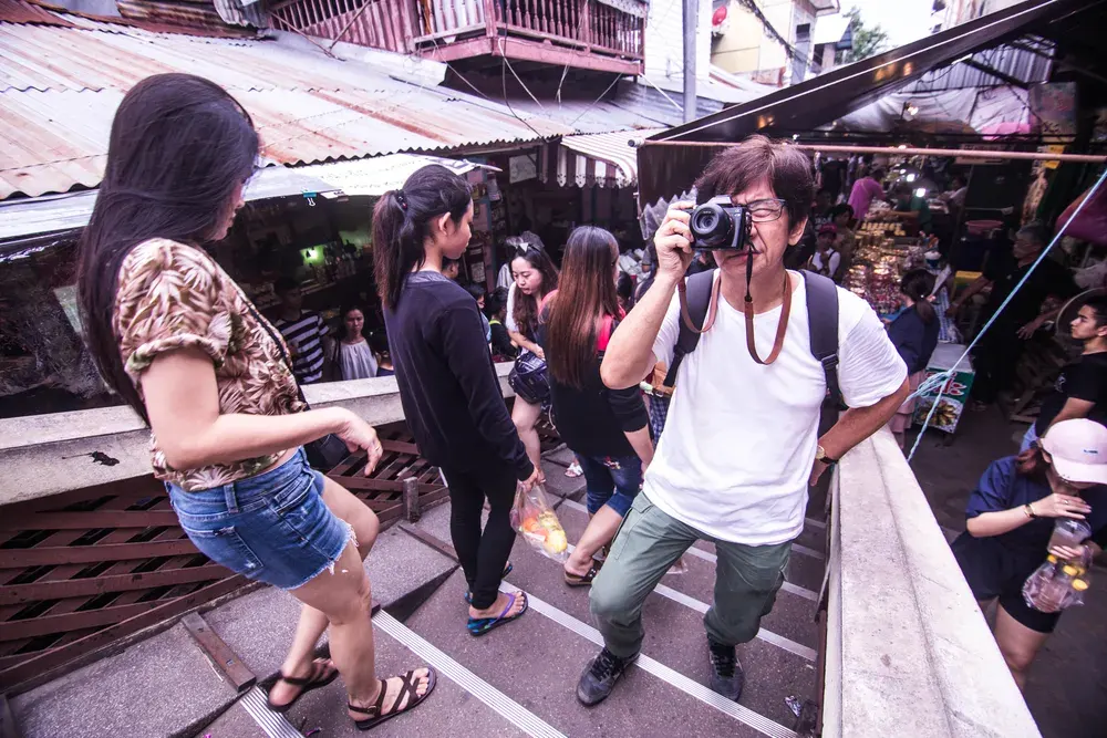 Colorful scene in a bustling Bangkok market with a photographer capturing moments.