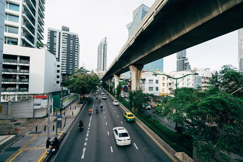 A vibrant urban scene depicting a busy street with cars and motorbikes in Bangkok, Thailand.