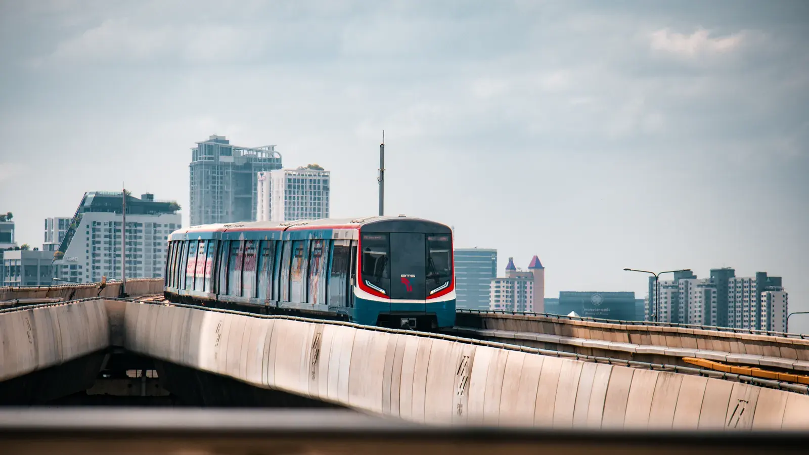 BTS Skytrain traversing urban Bangkok with skyscrapers in the background.