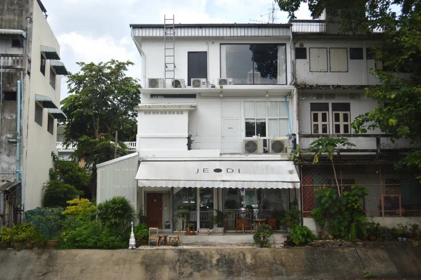 Charming urban cafe with a white facade in a peaceful street setting.