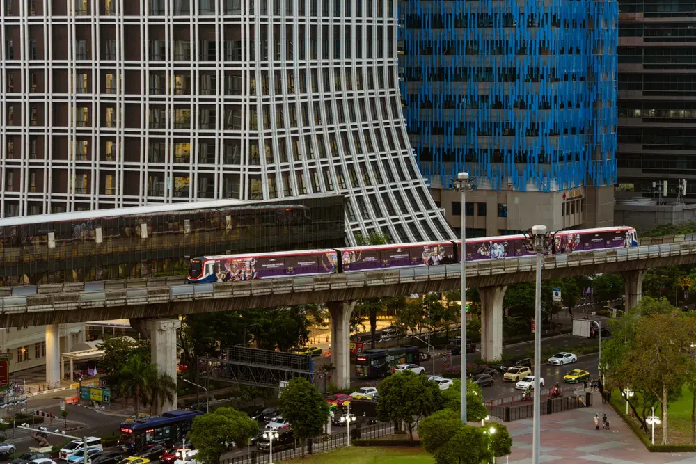 Skytrain traversing Bangkok amidst modern high-rise buildings, urban skyline view.