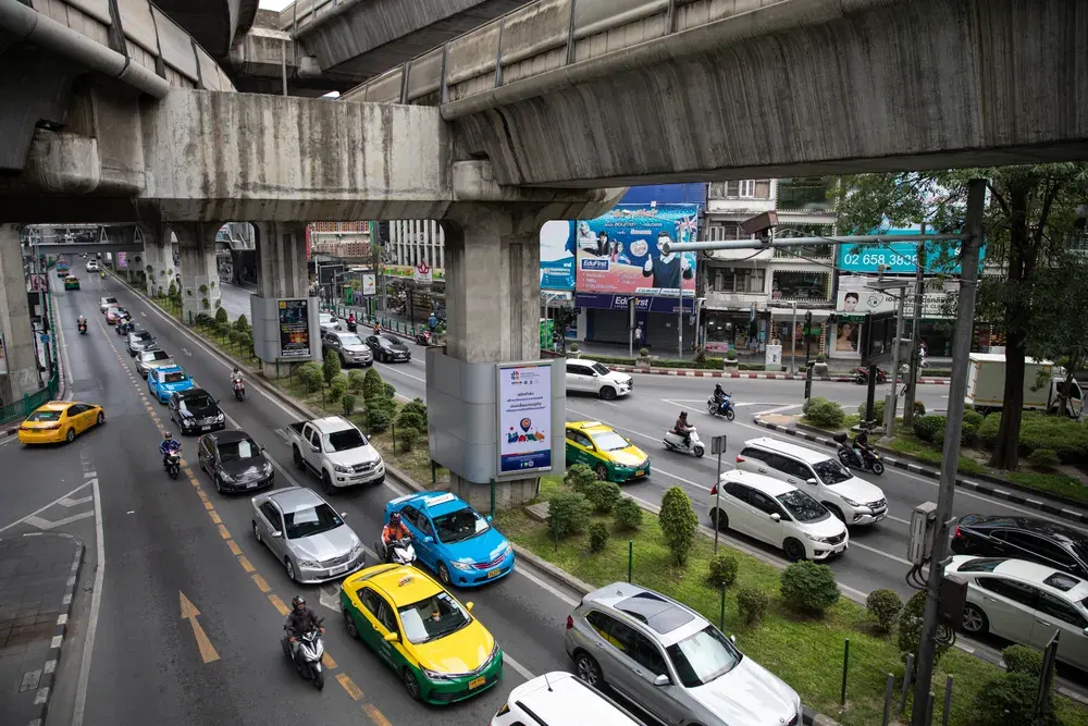 Aerial view of busy city traffic beneath a concrete overpass in Bangkok.