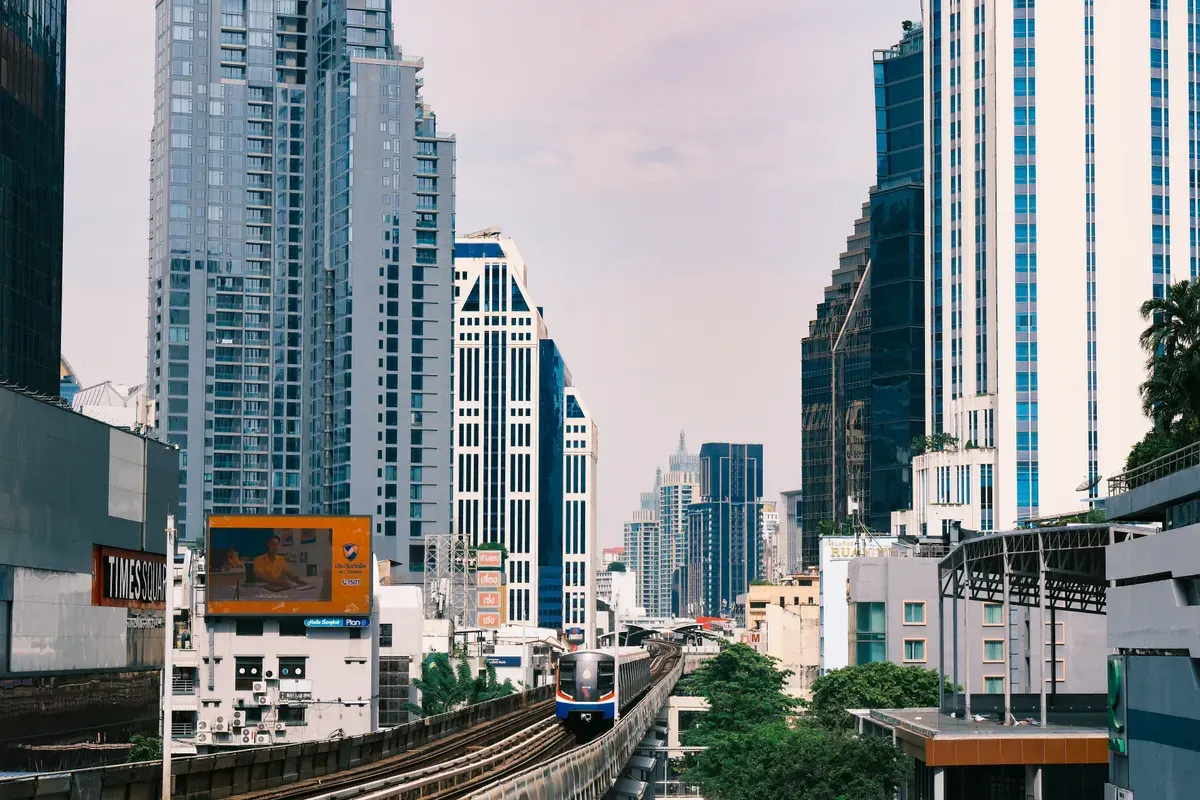 Modern Bangkok cityscape with skytrain and towering skyscrapers on a sunny day.